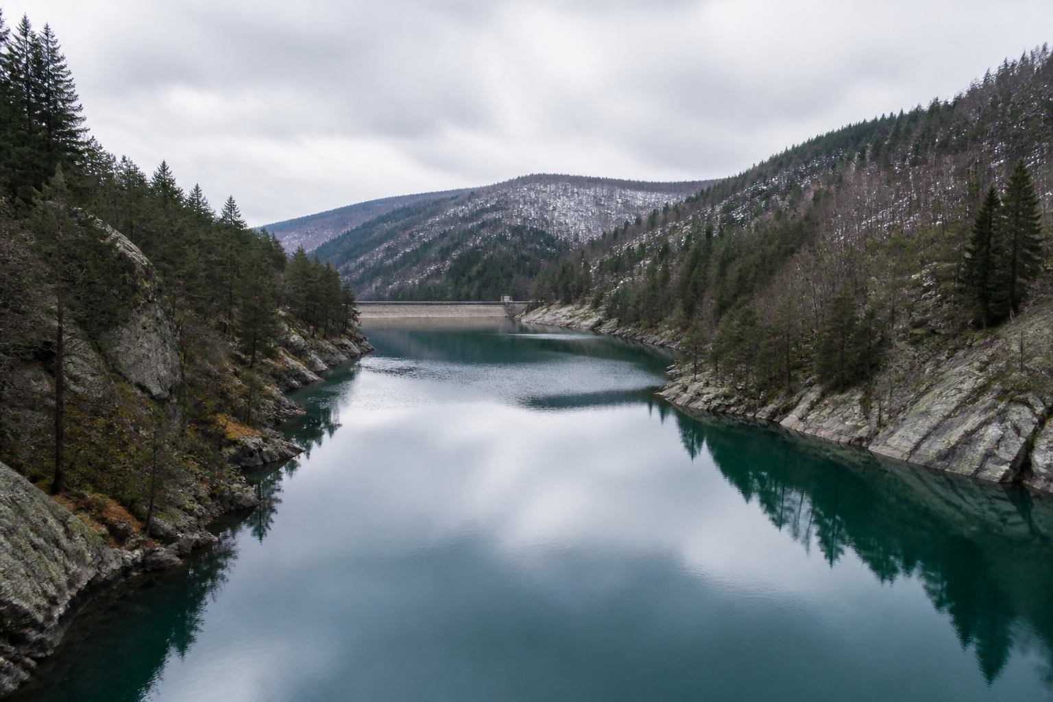 Kühler Stausee zwischen bewaldeten Granithängen